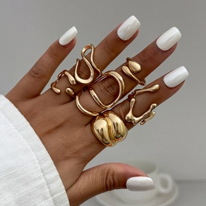 Detail of hand wearing stacked gold liquid metal rings with irregular flowing textures