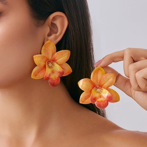 Detail of large orange orchid earrings with tropical petals and gold stamen accents