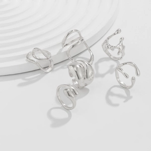 Set of six irregular silver molten liquid rings on a minimalist white stone display base