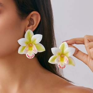 Close-up of lifelike orchid earrings with white-green petals and pink spotted details