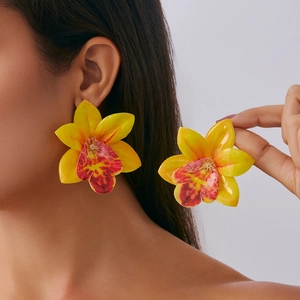 Close-up of bright yellow resin orchid flower statement earrings on model