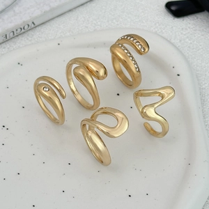 Detailansicht goldener unregelmäßiger Metallringe auf einem Keramiktablett