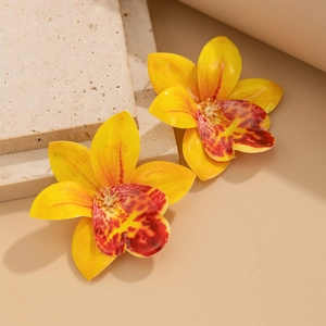 Macro detail of realistic yellow fabric orchid earring on neutral stone pedestal