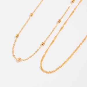 Detail of gold layered chains featuring round bead accents and twisted rope textures