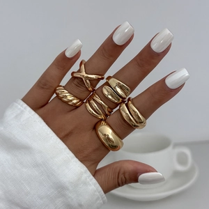 Close-up of minimalist gold teardrop and irregular geometric stacked rings on hand