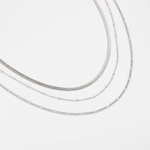 Detailed view of layered silver-tone necklaces including snake chain and figaro chain