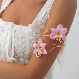 Detail of pink orchid arm cuff featuring golden double wrap metal band and floral decor