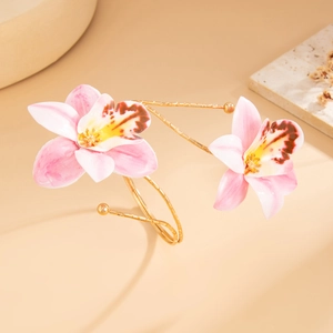 Detailed close-up of golden spiral cuff bracelet with realistic pink orchid flower charms