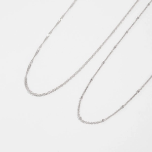 Detail of silver twisted rope and delicate beaded square link chain textures