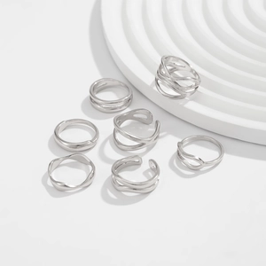 Macro detail of a 7-piece silver geometric ring set on a modern white display stand