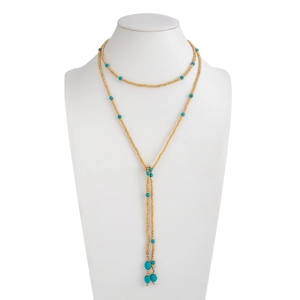 Detail van de Y-halsketting met gouden kralen en turquoise kwastjes op een witte buste