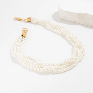 Detail of multi-strand white faux pearl waist chain with golden lobster clasps