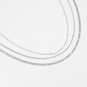 Detailed close-up of triple-layered silver chain necklace with Figaro and snake link styles