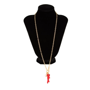 Collar largo dorado con colgante de coral rojo y perla blanca en un soporte negro