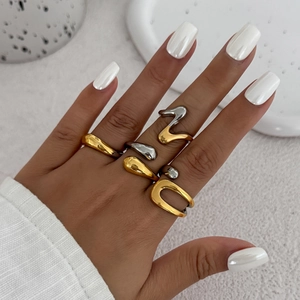 Detail of minimalist gold and silver teardrop rings featuring geometric open band design