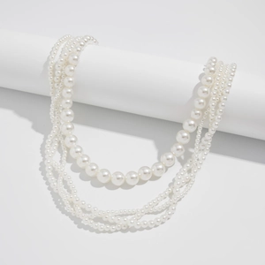 Detail of layered cream white pearl waist chain draped on a white column stand