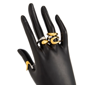 Detail view of irregular liquid metal rings in gold and silver on a hand model