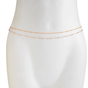 Detail view of a double-layered gold waist chain featuring delicate white beads and a sleek design
