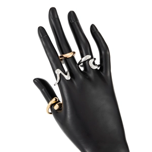Detailed view of modern wave-shaped rings in gold and silver finish on a display hand
