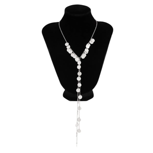 Detail van zilveren Y-ketting met gehamerde metalen schijven op zwarte fluwelen display