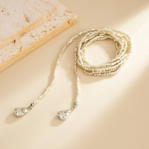 Detail van de kralenketting met champagne metalen kralen en zilveren druppelhangers