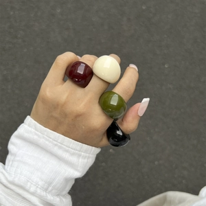 Modell trägt vier dicke Harzringe in Dunkelrot, Creme, Olivgrün und Schwarz