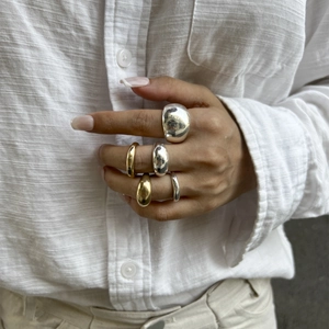 Gepolijste gouden en zilveren bolle ringen gedragen voor een minimalistische look