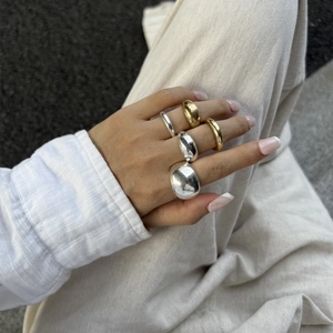 Detailopname van een minimalistische goud- en zilverkleurige druppelringenset op de hand