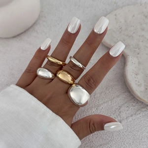 Gepolijste gouden en zilveren ringen op handen met minimalistische stenen achtergrond