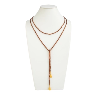 Detail van de lange Y-vormige ketting met bronzen kralen en gouden hangers