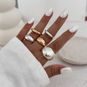 Detailweergave van gelaagde minimalistische goud- en zilveren ringen aan de hand van een model