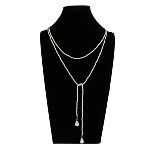 Detail van een gelaagde zilveren kralenketting met een Y-vormige lariat en druppelhangers