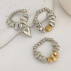 Dettaglio di anelli in stile industriale con ciondolo a cuore e perle miste in argento