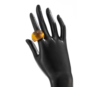 Detail eines bernsteinfarbenen klobigen Acrylrings auf einem schwarzen Handmodell
