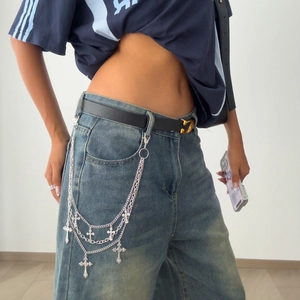 Detail of silver multi-layered punk waist chain with cross pendants on denim jeans