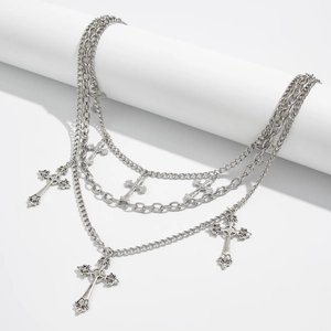 Detail of triple-layer gothic silver necklace with five ornate cross pendants on white stand