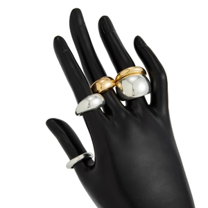 Detailopname van gestapelde gouden en zilveren chunky ringen op een handmodel