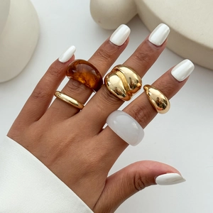 Gestapelde set geometrische goudmetalen ringen en amberhars ringen gedragen door model
