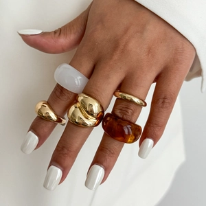 Set van grove gouden en hars ringen gedragen op een hand in een minimalistische modestijl