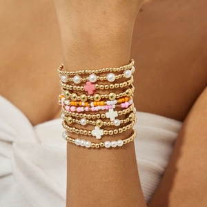 Détail de bracelets bohèmes superposés avec perles et breloques de croix en acrylique