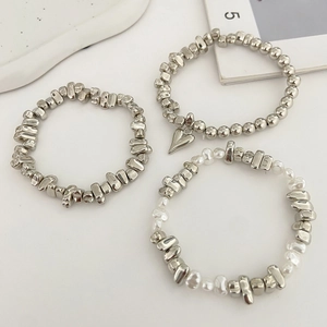 Vista macro di braccialetti elastici con perline d'argento e perle barocche bianche
