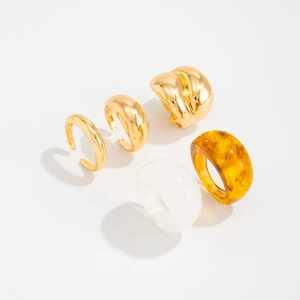 Detail van een 5-delige stapelbare ringenset met goud metaal en amberkleurig hars