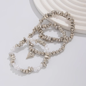 Dettaglio del set di tre braccialetti argentati con ciondolo a cuore e perle