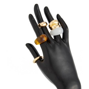 Detail van geometrische gouden metalen ringen en barnsteenhars ringen op handmodel