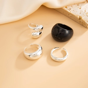 Detailweergave van minimalistische zilveren lava-ringen en zwarte harsringen op decor