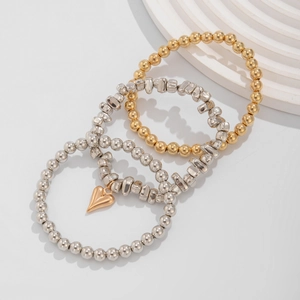 Dettaglio del set di 4 braccialetti di perline con ciondolo a cuore dorato e sfere in metallo