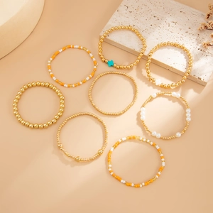Détail des perles dorées bohèmes et pendentifs croix sur un lot de 8 bracelets élastiques