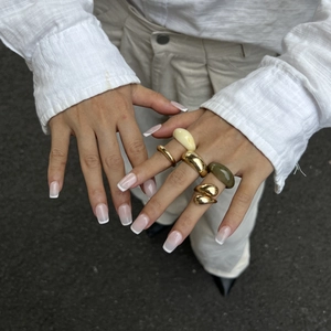 Detail van vijf gemengde gouden metalen en hars ringen gedragen als een set aan de hand