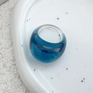 Detailansicht eines klobigen Acrylrings mit tiefblauem Wirbeldesign auf weißem Tablett