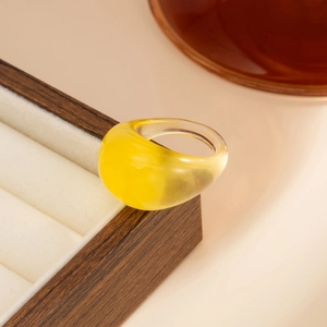 Makroaufnahme eines minimalistischen, durchsichtigen bernsteingelben Harzrings auf Holz